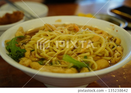 Delicious Korean style udon noodle soup with green vegetables in a white bowl, close up shot Delicious Korean style udon noodle soup with green vegetables in a white bowl, close up shot 135238642