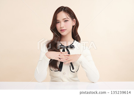 A beautiful young Asian woman with clean, fresh skin against a beige background. Skincare, facial treatment, cosmetology, beauty, and spa. An elegant portrait of an Asian woman. A beautiful young Asian woman with clean, fresh skin against a beige background. Skincare, facial treatment, cosmetology, beauty, and spa. An elegant portrait of an Asian woman. 135239614