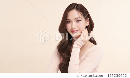 A beautiful young Asian woman with clean, fresh skin against a beige background. Skincare, facial treatment, cosmetology, beauty, and spa. An elegant portrait of an Asian woman. 135239622