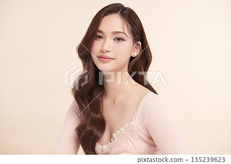 A beautiful young Asian woman with clean, fresh skin against a beige background. Skincare, facial treatment, cosmetology, beauty, and spa. An elegant portrait of an Asian woman. 135239623