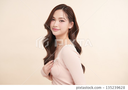 A beautiful young Asian woman with clean, fresh skin against a beige background. Skincare, facial treatment, cosmetology, beauty, and spa. An elegant portrait of an Asian woman. A beautiful young Asian woman with clean, fresh skin against a beige background. Skincare, facial treatment, cosmetology, beauty, and spa. An elegant portrait of an Asian woman. 135239628