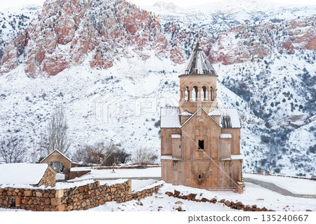 Noravank Monastery stands in snow-covered mountain gorge in Armenia, dramatic red cliffs, winter light, architectural presence, serene atmosphere Noravank Monastery stands in snow-covered mountain gorge in Armenia, dramatic red cliffs, winter light, architectural presence, serene atmosphere 135240667