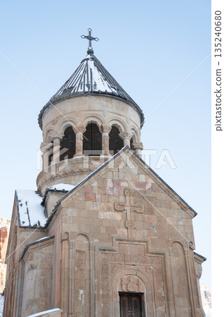 Noravank Monastery stands in snow-covered mountain gorge in Armenia, dramatic red cliffs, winter light, architectural presence, serene atmosphere Noravank Monastery stands in snow-covered mountain gorge in Armenia, dramatic red cliffs, winter light, architectural presence, serene atmosphere 135240680