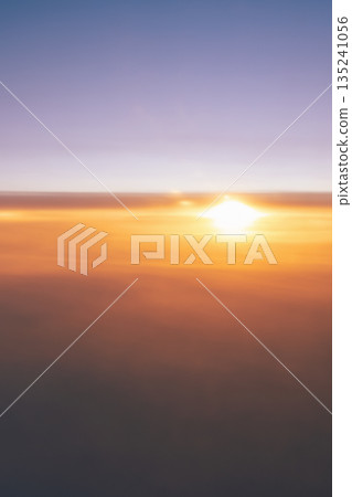 The orange sun over the sunset sky, the view from the airplane window flying over the clouds at sunset is a beautiful backdrop for travel copy space. High quality photo 135241056