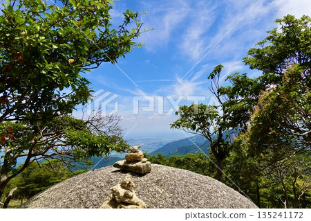 Gozaisho Mountain Park: A view of Ise Bay in the distance through pebbles piled up on a large rock. Komono Town, Mie County, Mie Prefecture 135241172