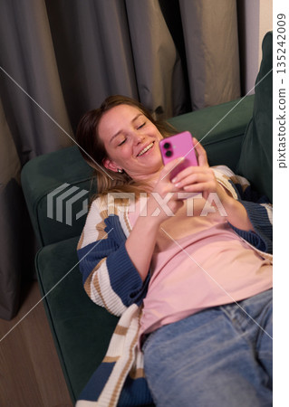 Woman lying on sofa using smartphone indoors Woman lying on sofa using smartphone indoors 135242009