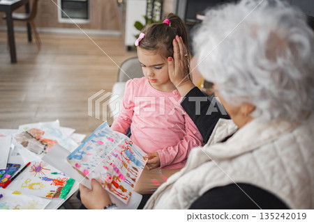 Grandmother admires child's artwork on a cozy afternoon 135242019