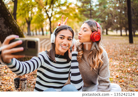 Capturing autumn joy with friends in the park while listening to music Capturing autumn joy with friends in the park while listening to music 135242124