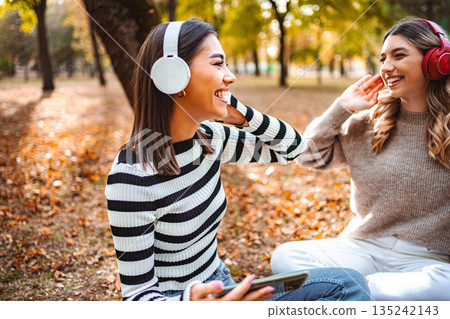 Friends enjoying music together during a vibrant autumn afternoon in the park Friends enjoying music together during a vibrant autumn afternoon in the park 135242143