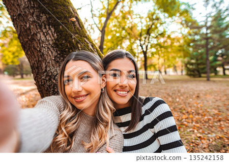 Autumn moments shared by two friends in a serene park setting Autumn moments shared by two friends in a serene park setting 135242158
