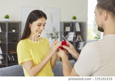Man holding ring box proposing to his beloved girlfriend in romantic moment 135242419