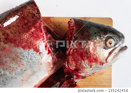 Raw rainbow trout fish head and body cut on a wooden chopping board. Fresh seafood preparation flat lay Raw rainbow trout fish head and body cut on a wooden chopping board. Fresh seafood preparation flat lay 135242458