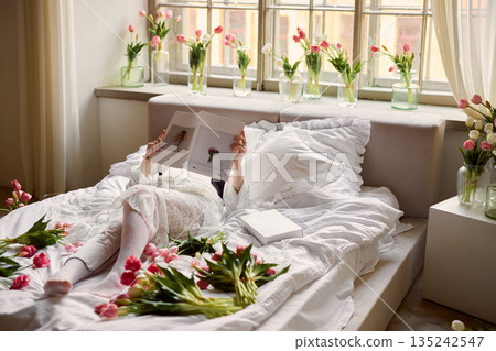 Person experiencing calm and restful morning surrounded by vibrant flowers and soft textiles Person experiencing calm and restful morning surrounded by vibrant flowers and soft textiles 135242547