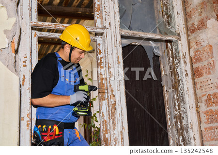 Interior renovator checking drill alignment near window Interior renovator checking drill alignment near window 135242548