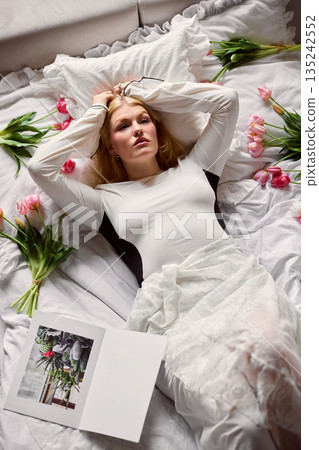 Relaxed woman enjoying peaceful morning rest, Serene woman lying with tulips and soft sunlight 135242552