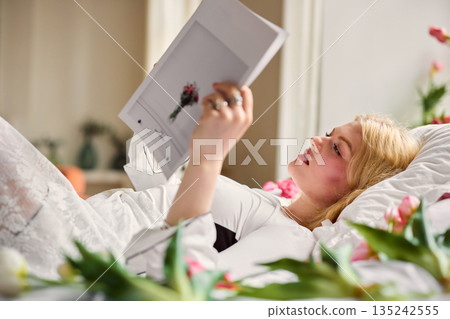 Serene lady enjoying peaceful sunrise moment, Tranquil female in bed with blooming tulips at dawn Serene lady enjoying peaceful sunrise moment, Tranquil female in bed with blooming tulips at dawn 135242555