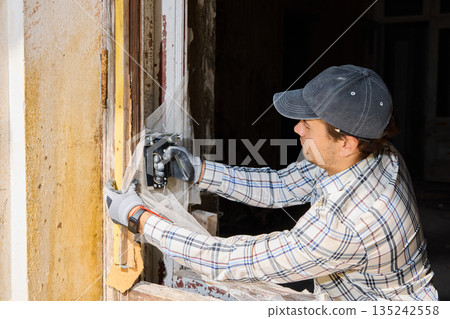 Craftsman polishing wooden window frame with safety gear and sparks Craftsman polishing wooden window frame with safety gear and sparks 135242558