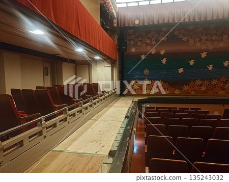 A traditional theater auditorium with rows of red seats 135243032
