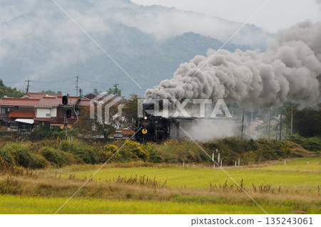 山口號蒸汽機車呼嘯著駛過鄉間,滾滾黑煙滾滾而來。 山口號蒸汽機車呼嘯著駛過鄉間,滾滾黑煙滾滾而來。 135243061