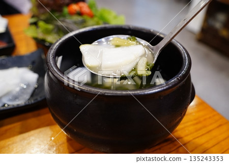 Authentic Korean radish water kimchi (Dongchimi) in a black stone bowl, close up shot 135243353