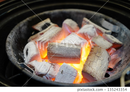 High quality Japanese Binchotan white charcoal glowing in a black metal grill 135243354