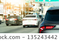 Rear side of modern grey car driving on asphalt road with traffic jam. Urban city transportation concept with bright sunlight flare background during rush hour. 135243442