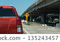 Rear view of a orange pickup truck driving on the asphalt road under a concrete bridge with a yellow traffic sign indicating a split path. Transportation concept. 135243457