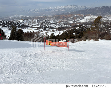 Orange slow sign on snowy ski slope at ski resort. Orange slow sign on snowy ski slope at ski resort. 135243522