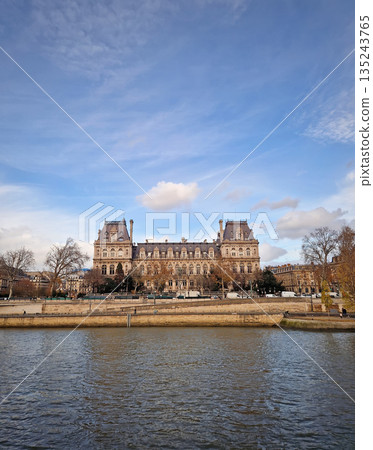 Beautiful view of the Hotel de Ville from the Seine riverside, showing the grand Neo-Renaissance facade and the riverbanks lined with trees and stone embankments Beautiful view of the Hotel de Ville from the Seine riverside, showing the grand Neo-Renaissance facade and the riverbanks lined with trees and stone embankments 135243765