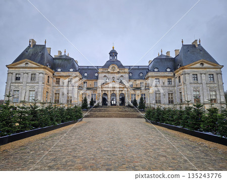 Maincy, France - December 11, 2025: Grand facade of Chateau de Vaux-le-Vicomte with cobblestone courtyard. Beautiful Baroque architecture decorated with small evergreen trees for the winter holidays Maincy, France - December 11, 2025: Grand facade of Chateau de Vaux-le-Vicomte with cobblestone courtyard. Beautiful Baroque architecture decorated with small evergreen trees for the winter holidays 135243776