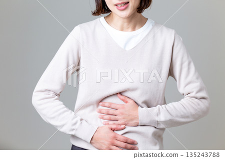 A middle-aged woman holding her stomach and suffering from stomach pain A middle-aged woman holding her stomach and suffering from stomach pain 135243788