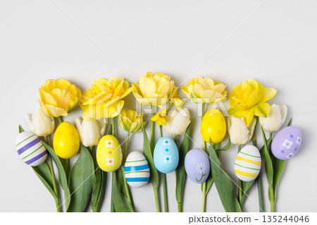 Easter colored painted eggs and yellow daffodils and tulips on gray background with space for text and greetings. Easter and spring concept. Spring background Easter colored painted eggs and yellow daffodils and tulips on gray background with space for text and greetings. Easter and spring concept. Spring background 135244046