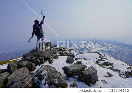 冬季,一名登山者手持冰鎬站在羅臼山頂峰。 冬季,一名登山者手持冰鎬站在羅臼山頂峰。 135244320