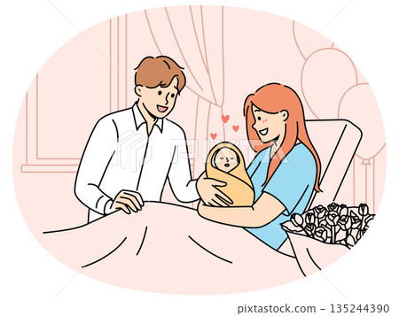 Mother with newborn baby sits on couch in hospital and shows infant to happy father Mother with newborn baby sits on couch in hospital and shows infant to happy father 135244390