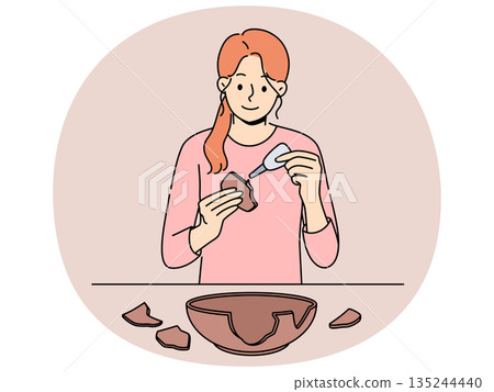 Woman seals broken clay plate to hide carelessness or demonstrate conscious consumption 135244440