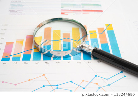 Magnifying glass on charts graphs paper. 135244690