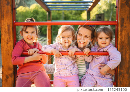 Smiling mom with daughters on the playground 135245100