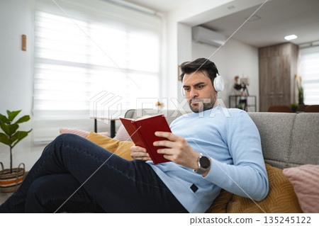 Man Reading Book on Couch 135245122