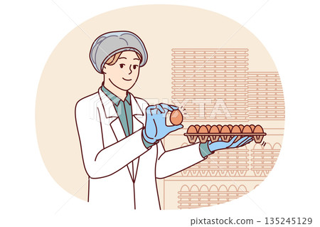Woman factory worker holds chicken eggs while checking finished product for quality 135245129
