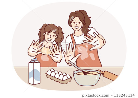 Mom and daughter are preparing breakfast or pastries and with smile show palms stained with flour 135245134