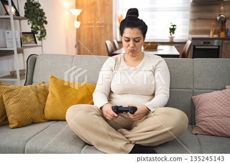 Competitive woman playing video game at home 135245143