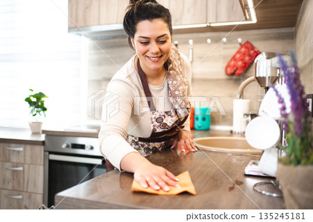 Woman in apron cleaning kitchen counter 135245181