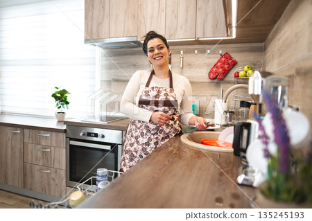 Happy woman wearing apron in the kitchen 135245193