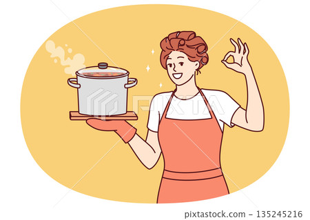 Woman housewife or cook with soup pan shows ok gesture and looks at screen smiling 135245216