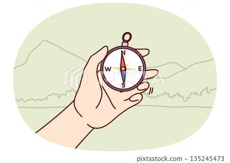 Compos in hand of person went on hike and determines direction of world to find way 135245473