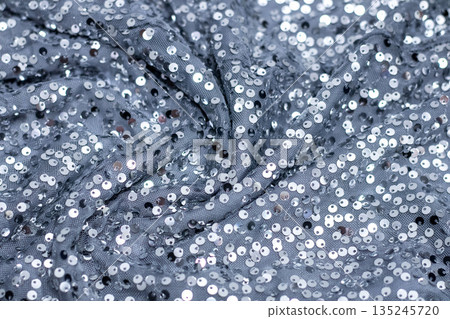 Blue sequin fabric draped in shimmering folds, glamorous texture for fashion and party style 135245720