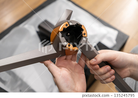 A person carefully unboxes and assembles a sophisticated grey and bronze appliance component, showcasing modern innovative design and smart home technology integration A person carefully unboxes and assembles a sophisticated grey and bronze appliance component, showcasing modern innovative design and smart home technology integration 135245795