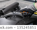 Gloved hand precisely using a ratchet wrench to assemble or repair electronic equipment, symbolizing meticulous maintenance, technical support, and professional service 135245851