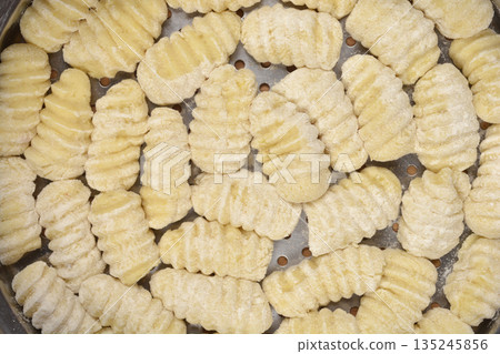 Large Group of Fresh Uncooked Potato Gnocchi in a Metal Steamer 135245856