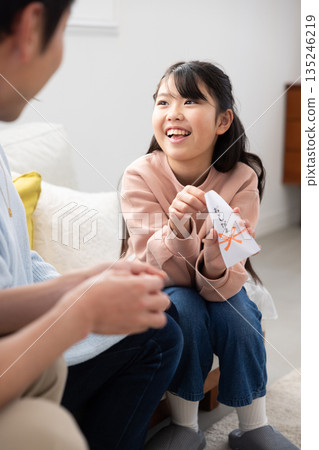 一位笑容燦爛的小學生從父母那裡收到了新年壓歲錢。 一位笑容燦爛的小學生從父母那裡收到了新年壓歲錢。 135246219